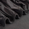 Black elastic sofa slipcovers draped and folded on a dark gray fabric.