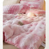 A pink and white plaid plush rabbit quilt comforter with a fluffy texture is displayed on a bed.