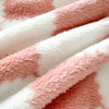 A close-up of a soft flannel panda fleece blanket featuring a white and dusty rose mottled pattern.