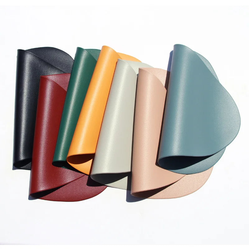 A collection of reusable vinyl placemats in various muted colors, including black, green, orange, beige, and blue-gray.