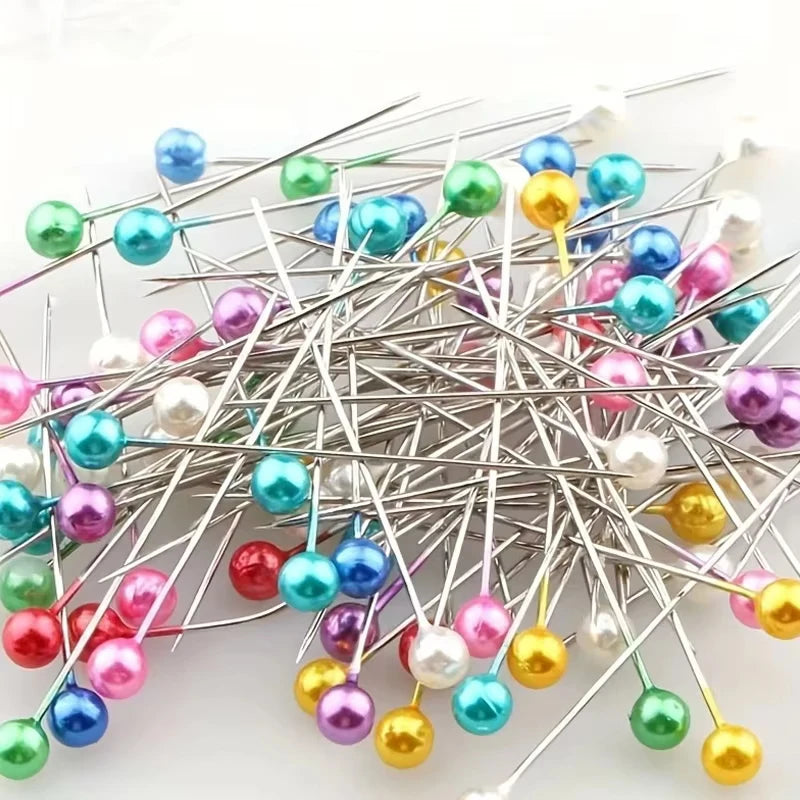 A cluster of decorative sewing and pinning needles with various colored beads and tips.