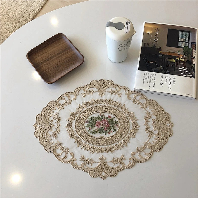 An elegant oval lace embroidered coaster set featuring floral designs on a white background.