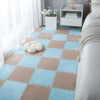 A light blue and beige interlocking puzzle rug mat placed on a bedroom floor with white curtains and a bedside table.