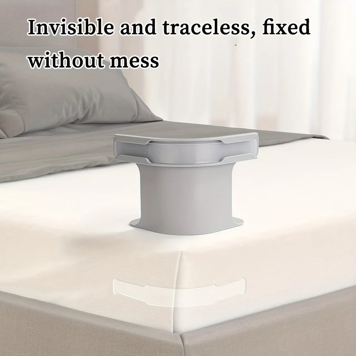 A close-up view of a gray adjustable bed sheet holder with a non-slip grip resting on a white bed sheet.