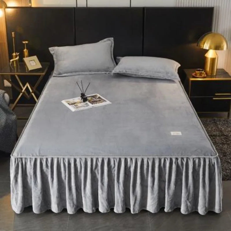 A thick milk velvet bed skirt with gathered fabric and soft pillows on a dark bed.