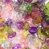 A close-up of various translucent resin flower bead caps in shades of pink, purple, green, and amber.