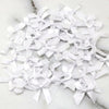 A pile of small white satin ribbon bows for crafts and decor scattered on a white marble surface.