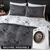 A set of three gray floral print duvet covers and pillowcases displayed on a bed next to a white washing machine.