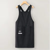 Black water-resistant kitchen apron hanging on a wooden hanger.