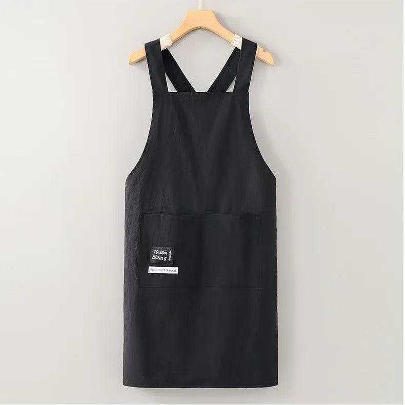 Black water-resistant kitchen apron hanging on a wooden hanger.