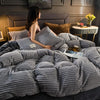 A gray ultra-soft corduroy duvet cover set displayed on a bed with a headboard and bedside table.