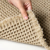 A hand is touching a beige waffle texture bath mat for floors.