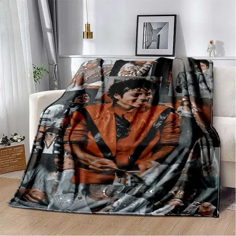 A dark flannel blanket featuring a collage of black and white photographs of musicians and performers.