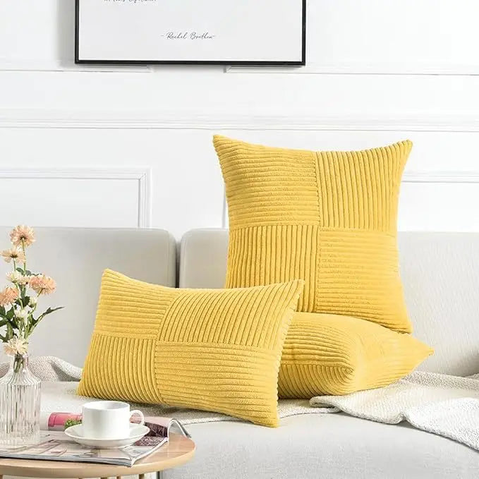 A collection of yellow retro corduroy patchwork pillow covers arranged on a light gray sofa.