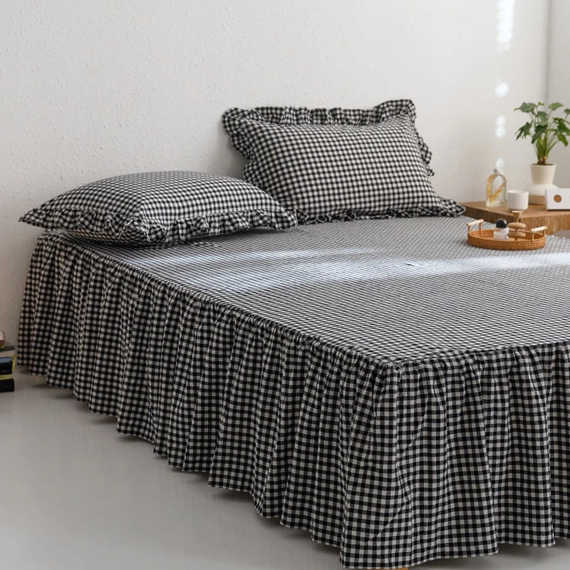 A black and white plaid cotton bed skirt cover with matching pillowcases on a bed.