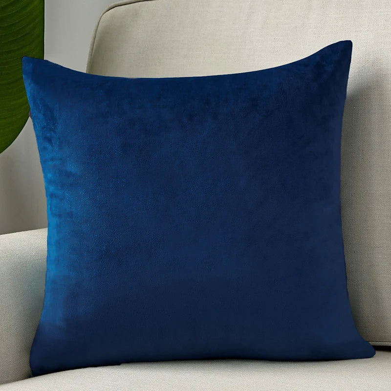 A deep navy blue velvet cushion cover resting on a light gray sofa.