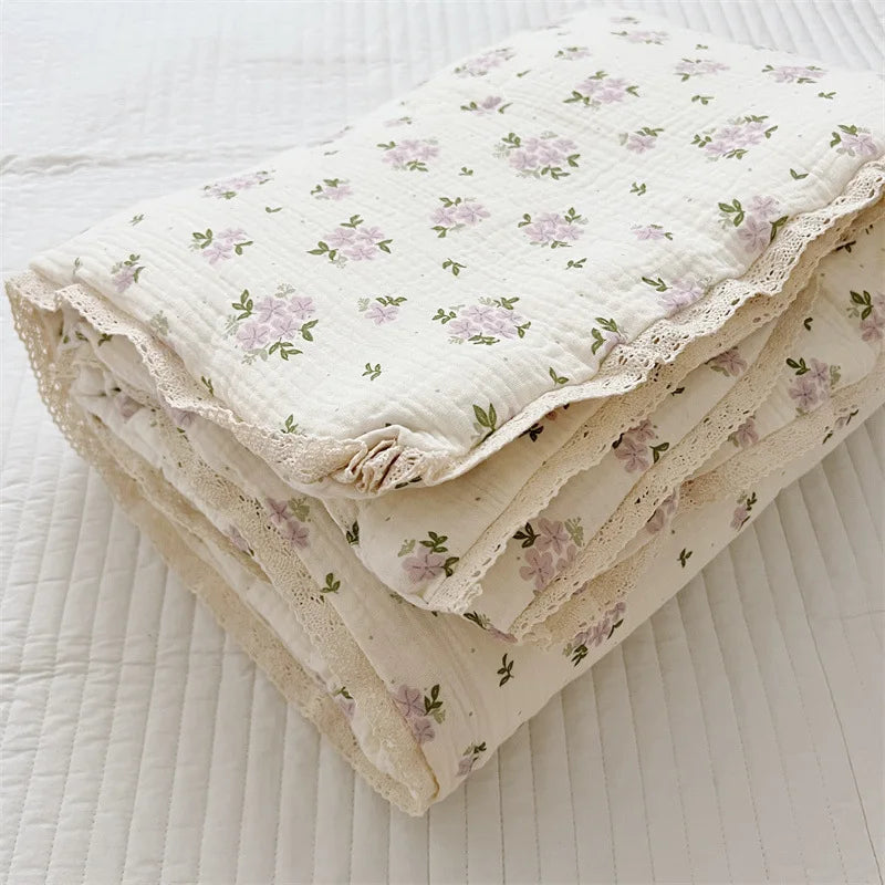 A stack of floral print muslin blankets for baby, folded and lying on a white surface.