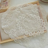 Elegant oval lace embroidered coaster set with delicate white floral patterns on a light beige background