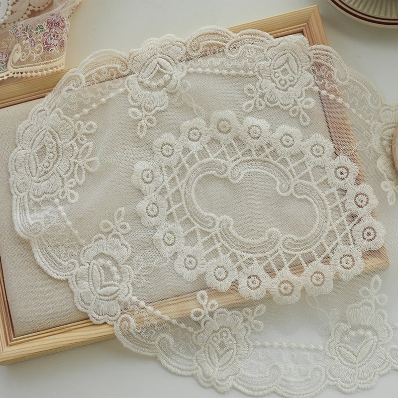 Elegant oval lace embroidered coaster set with delicate white floral patterns on a light beige background