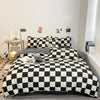 A black and white plaid duvet cover set displayed on a bed with decorative wall art.