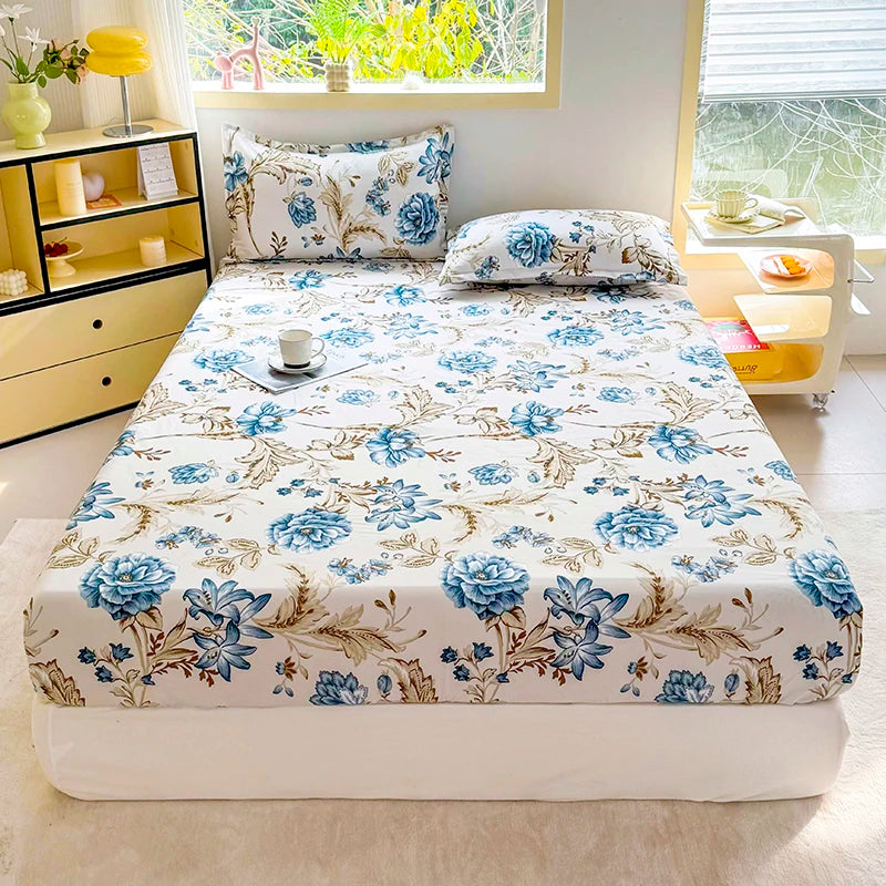 A floral print fitted bed sheet with blue and beige flowers is displayed on a white bed.