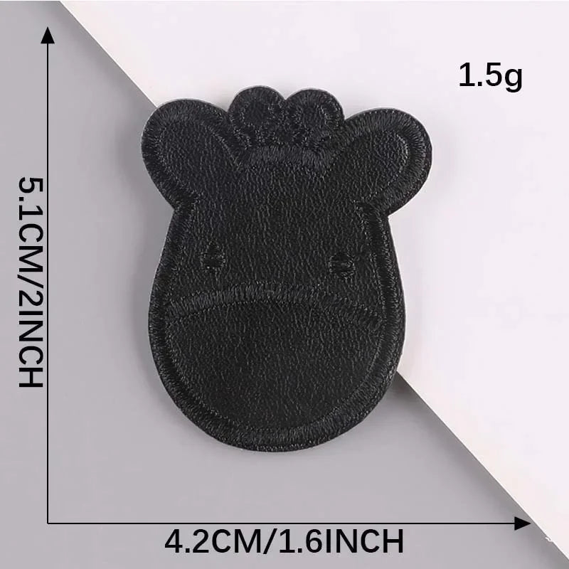 A black embroidered leather patch shaped like a cow's head with a self-adhesive backing.