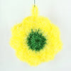 A bright yellow flower shaped kitchen dish scrubber sponge with a green center.