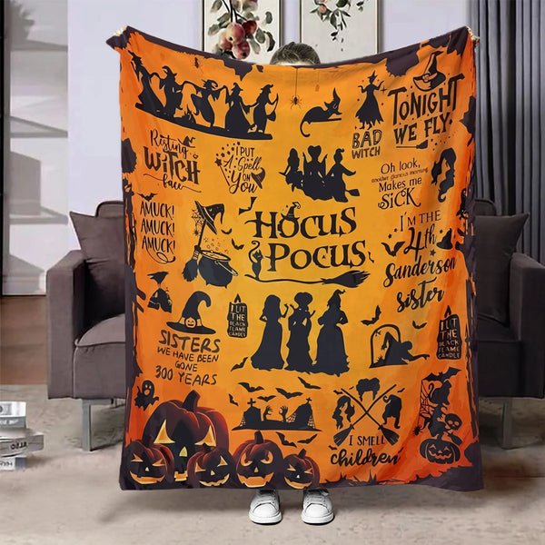 An orange flannel throw blanket featuring black silhouette designs of witches, bats, and Halloween figures.