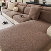 A brown jacquard sofa cover featuring a branch pattern and cream accent pillows on a beige sofa.