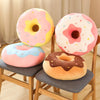A set of pink and yellow donut-shaped plush pillows resting on wooden chairs.