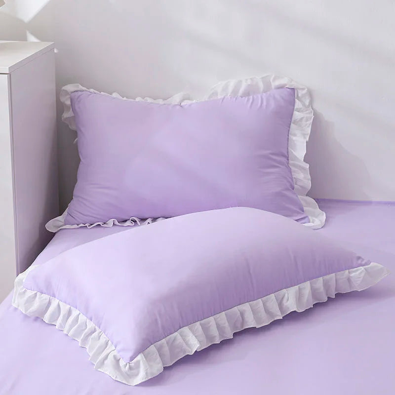 A purple ruffled pillowcase with a white trim is displayed on a bed.