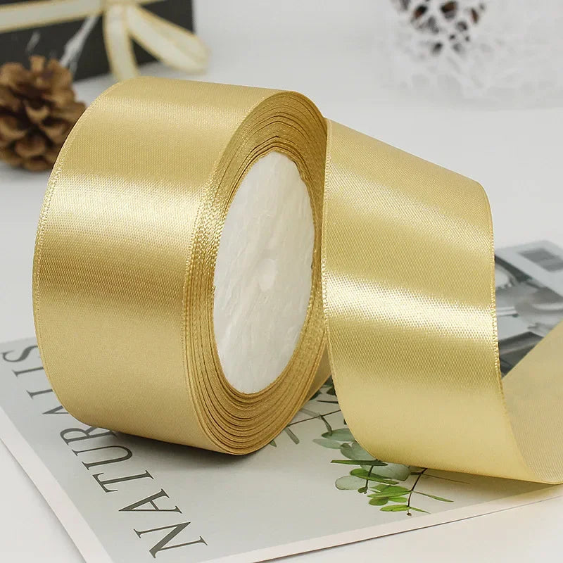 Roll of gold satin ribbon with white center, lying on a sheet of paper.
