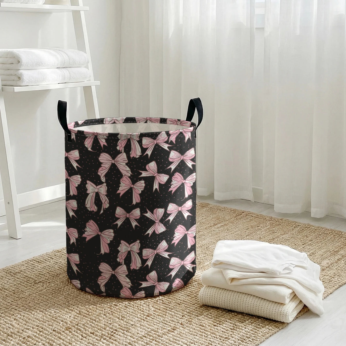 A black and pink patterned foldable canvas laundry basket sitting on a woven mat next to white towels.