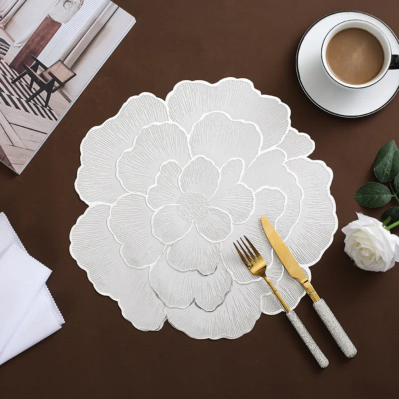 White gold plated peony coasters displayed on a dark brown surface with a cup and silverware.