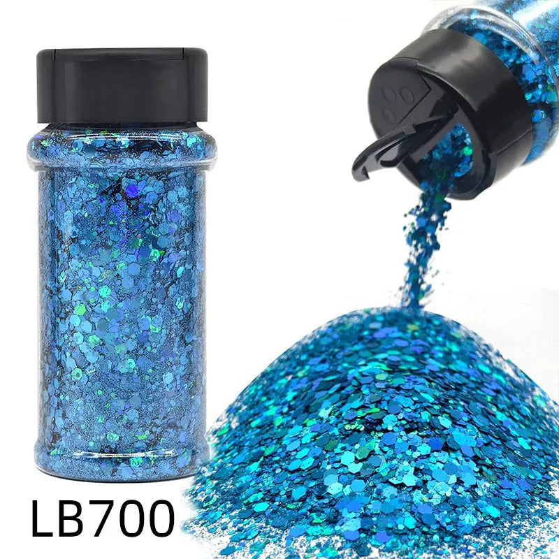 A bottle of LB700 holographic blue glitter being poured onto a pile of sparkling blue craft glitter.