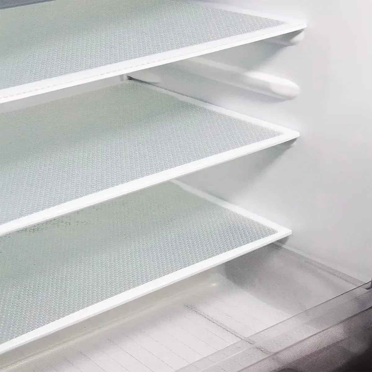 White plastic shelf liners are installed in a refrigerator, showing multiple levels of storage.