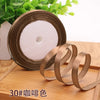 Roll of satin ribbon with several coils unwound on a wooden surface