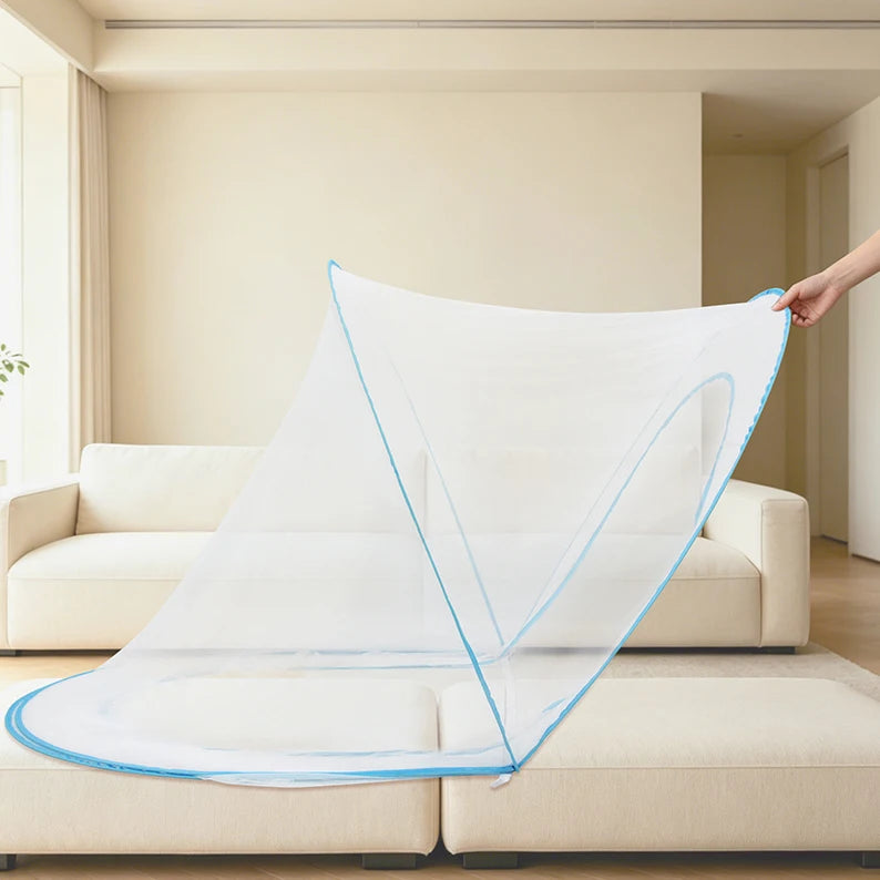 A transparent white portable mosquito net is draped over a light-colored sofa in a bright living room.