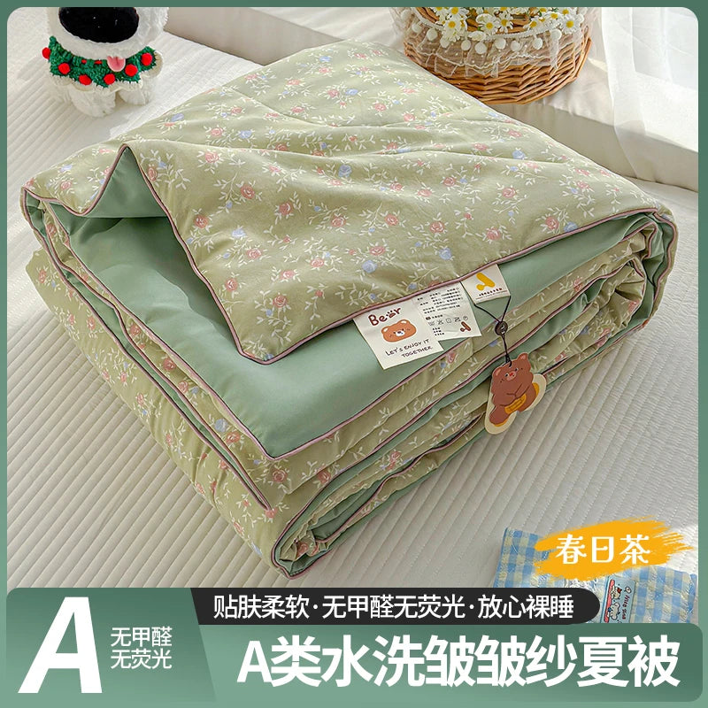 A lightweight summer quilt with a floral pattern shown folded on a white surface.