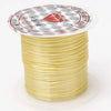 A spool of yellow elastic beading cord with a circular label featuring a red diamond design and Japanese text.