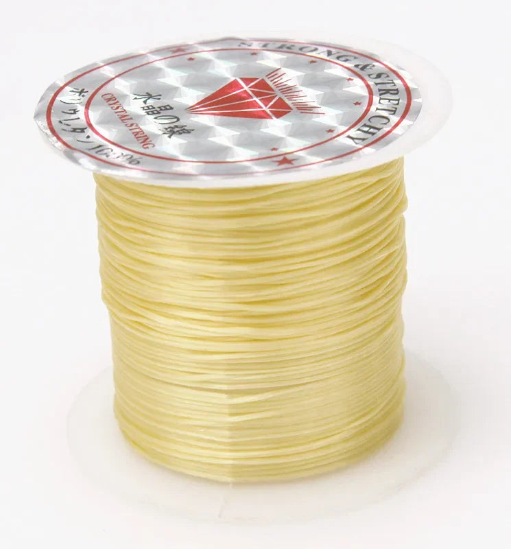 A spool of yellow elastic beading cord with a circular label featuring a red diamond design and Japanese text.