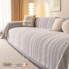 A beige chenille blanket featuring a black fishbone pattern draped over a sofa.