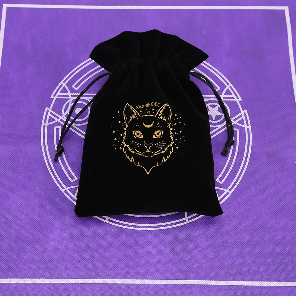 A black velvet pouch with a gold-colored cat face design rests on a purple surface.