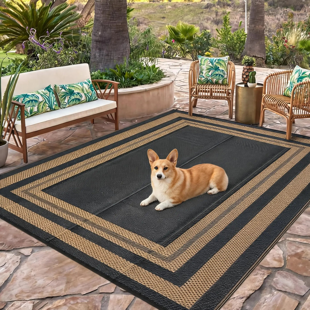 A black and gold reversible outdoor patio rug with a patterned design placed on a stone patio.