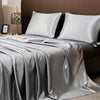 A luxury solid satin bedding set featuring silver gray sheets and pillows on a bed.