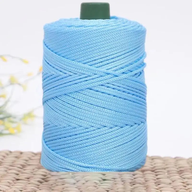 A spool of light blue 3mm ice rope crochet yarn for crafting resting on a woven surface.
