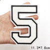 A white letter patch shaped like the number five is held in a hand.