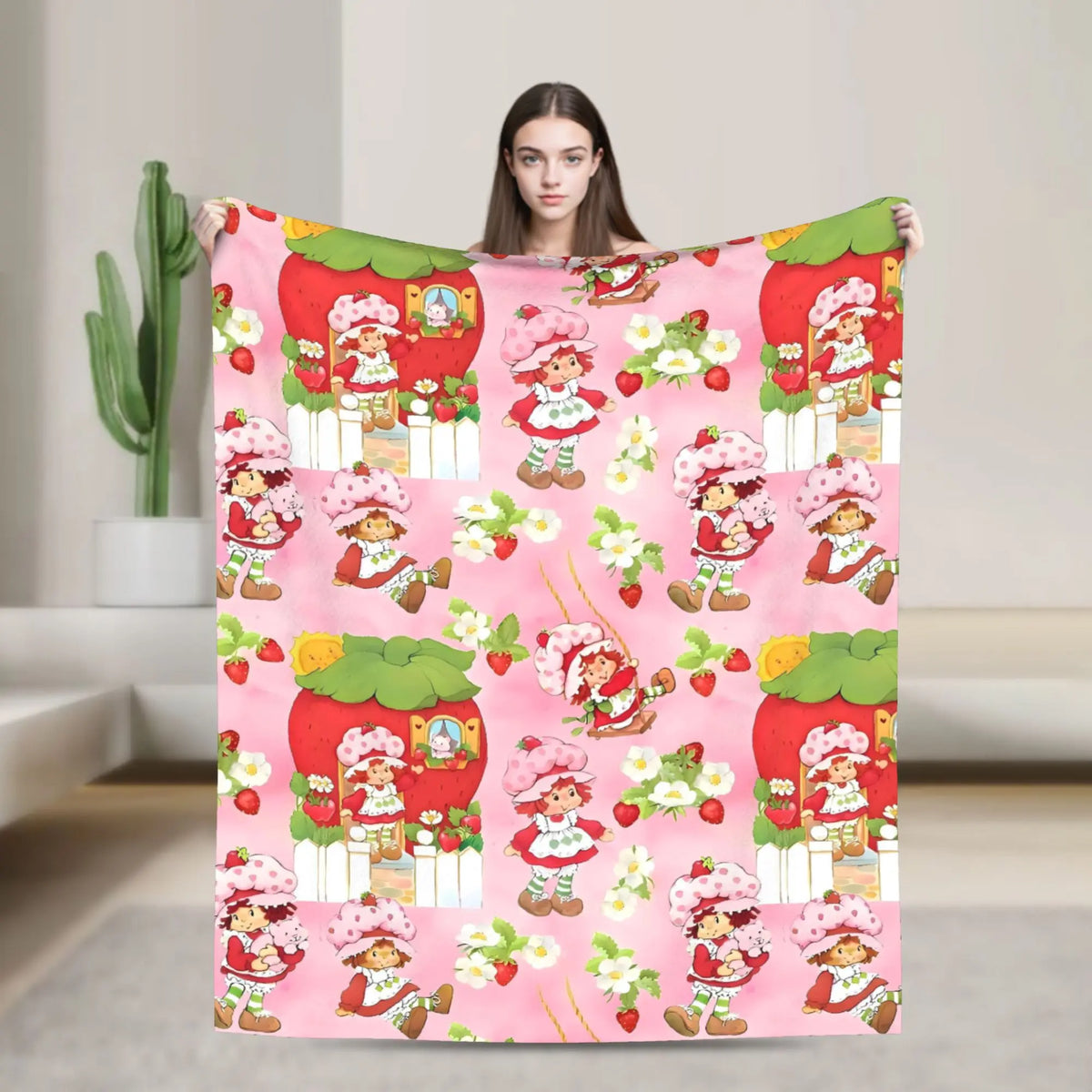 A pink strawberry shortcake plush throw blanket featuring characters and fruit designs.