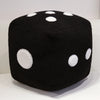 A black cube shaped plush toy with white polka dots, used as a throw pillow.