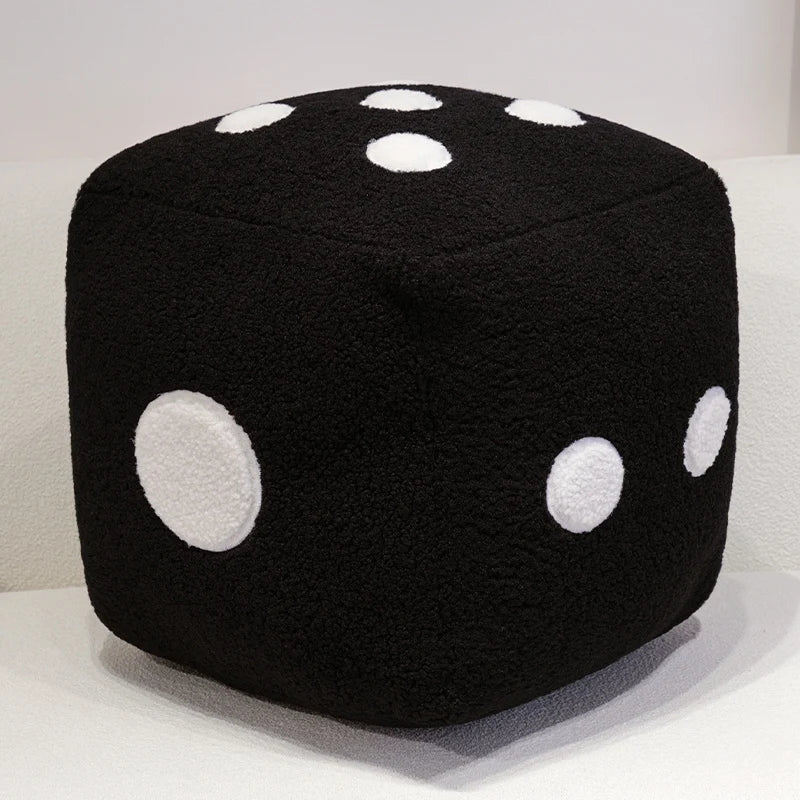 A black cube shaped plush toy with white polka dots, used as a throw pillow.